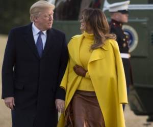 Donald Trump intenta tomar la mano a Melania, pero ella lleva los brazos en la parte interior de su abrigo amarillo. Ambos cruzan el césped de la Casa Blanca. Fotos cortesía AFP