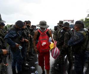 Un migrante hondureño, parte de una caravana que se dirige a los Estados Unidos, camina bajo la lluvia junto a miembros del Ejército de Guatemala, en Entre Ríos, Guatemala, luego de cruzar la frontera desde Honduras. Foto: Agencia AFP.