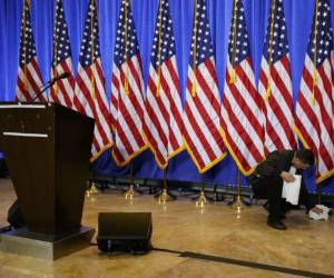 Un empleado de la Trump Tower limpia banderas mientras prepara el lugar donde Donald Trump dará su primera conferencia de prensa como presidente electo, en Nueva York, el 11 de enero de 2017. Foto: AP