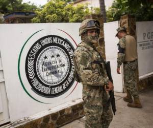 Un infante de Marina, al frente, y un miembro de la Guardia Nacional, atrás, vigilan afuera de una oficina de la Procuraduría General de la República adonde son enviados los migrantes antes de ser transferidos a Tapachula desde Arriaga, México, el domingo 23 de junio de 2019. (AP Foto/Oliver de Ros)