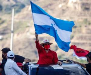 A lo largo de la campaña electoral se pudo ver a Xiomara Castro alzando la Bandera Nacional en color azul turquesa en diferentes actos políticos. Foto: Cortesía