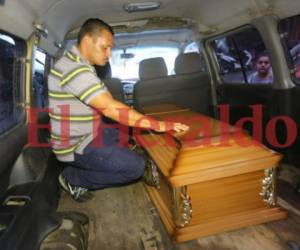 El padre del menor pone su mano derecha sobre el féretro, luego de ser retirado de la morgue capitalina. Foto: Estalin Irías/EL HERALDO.