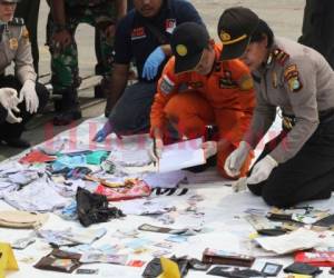 Los restos del avión y pertenencias personales del pasaje, incluyendo documentación, ropa y maletas que fueron hallados esparcidos en el mar, se extendieron sobre lonas en un puerto al norte de Yakarta antes de ser clasificadas en bolsas para evidencias.