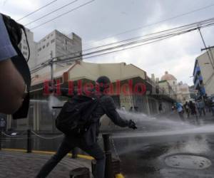 Momento en que autoridades lanzan agua y gases lacrimógenos a los encapuchados enfrente del Parque Central. Foto Alejandro Amador| EL HERALDO