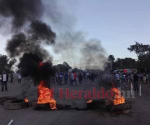 Imagen muestra el momento en el que los pobladores de San Antonio obstaculizaron el paso encendiendo llantas, mientras portaban la bandera hondureña y carteles.