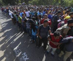 Migrantes forman una cadena sujetándose por los brazos en una carretera hacia Tapachula, México. Foto: Agencia AP.