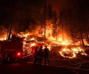 Los bomberos intentan controlar el voraz incendio. Foto AFP
