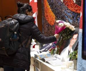 Una mujer deja flores junto a un libro de condolencias antes de una ceremonia en la Universidad de Carleton en memoria del estudiante de doctorado en biología Fareed Arastech, fallecido en el avión de Ukraine International Airlines estrellado en Teherán. Foto: AP.