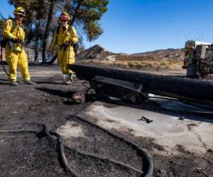 Bomberos de California examinan un poste de bajo voltaje calcinado en un incendio, el 25 de octubre de 2019, en Santa Clarita, California.