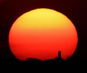 En esta fotografía de archivo del viernes 26 de junio de 2020, se ve a la distancia la puesta del sol atrás de una chimenea en Kansas City, Missouri. Foto: AP