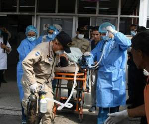 Miembros del cuerpo de bomberos y médicos del Hospital Universitario de Tegucigalpa transportan al bombero Oscar Madrid en una camilla. Foto agencia AFP