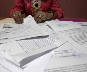 Una empresaria salvadoreña, quien es una de las solicitantes de un programa de reunificación familiar que fue clausurado por el presidente estadounidense Donald Trump, muestra documentos de las veces que ha denunciado robos y extorsiones, en Santa Ana, El Salvador. Dijo que se aterrorizó cuando comenzó a recibir amenazas de muerte en 2013. Los hombres con tatuajes iban a un lavado de autos que solía tener para exigir una 'compensación mensual' por dejarla operar. Asegura que ha recibido muchas amenazas desde entonces a través de llamadas, mensajes de texto y las redes sociales. Foto: AP.