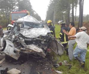 Miembros del Cuerpo de Bomberos de Honduras tratan de sacar el cadáver del vehículo que quedó completamente destruido.