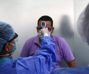 Personal sanitatorio toma la temperatura a un hombre en una pequeño centro médico en Lima, el miércoles 11 de marzo de 2020, como medida preventiva contra la propagación del nuevo coronavirus. La mayoría de la gente se recupera del COVID-19. AP