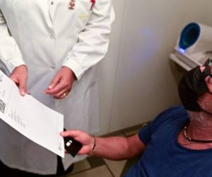 Zacco Cataldo, de 70 años, recibe un documento que acredita su vacunación contra el Covid-19, el 5 de agosto de 2021 en la farmacia Ambreck, en Milán. Foto: AFP