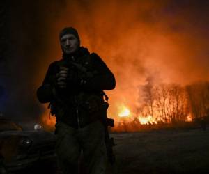 Un militar ucraniano mira mientras está de pie frente a un almacén en llamas después de un bombardeo en Kiev el 17 de marzo de 2022.