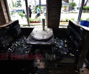 Los restos carbonizados de una mesa y bancos en un restaurante de comida rápida incendiada la víspera por saqueadores durante una protesta. Foto: Orlando Sierra/Agencia AFP.