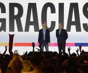 El presidente argentino Mauricio Macri (L), candidato presidencial del partido 'Juntos por el Cambio', y su socio Miguel Angel Pichetto gesticulan a sus votantes después de ser derrotados por el presidente electo Alberto Fernández del 'Frente de Todos'. Foto AFP