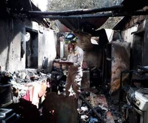 Miembros del Cuerpo de Bomberos evalúan los daños ocasionados por el voraz incendio.