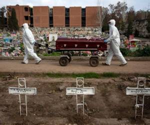 Por protocolo, para todos los entierros de fallecidos a causa de coronavirus los sepultureros del Cementerio General usan un traje especial, guantes, mascarillas y protección para el cabello. Foto: AFP