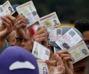 Un grupo de venezolanos sostienen una credencial migratoria para poder ingresar a Cúcuta en Colombia. Foto: Fernando Vergara | Agencia AP.