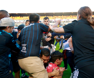 La imagen de este hombre abrazando a su hijo mientras son pateados por los aficionados del Querétaro se volvió viral.