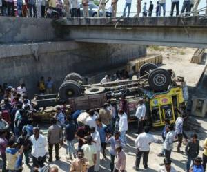 Los espectadores se reúnen en torno a los cadáveres de los pasajeros que viajaban en un camión que se hundió en un puente en el distrito de Bhavnagar. Foto AFP