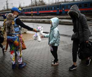 El británico David Fricker (2ndL) entrega un juguete de peluche, entre los miles de juguetes donados por niños británicos a través de la iniciativa de base Teddy Busz, a una joven refugiada ucraniana a su llegada a la estación de tren de Zahony a lo largo de la ruta ucraniana.