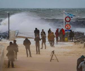 People stand on the beach as strong waves break against a jetty on the Belgian coast in Ostend on February 10, 2020, after storm Ciara swept over the country. - Hundreds of flights and train services were cancelled on February 10 as Storm Ciara sweeps over northwest Europe packing powerful winds, and leaving swatches of Europe without power after unleashing torrential rain and causing flash flooding. (Photo by KURT DESPLENTER / BELGA / AFP) / Belgium OUT