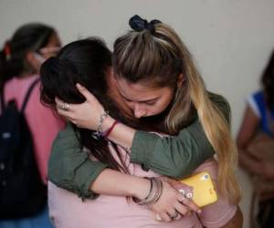 Amigas de Úrsula Bahillo, de 18 años y que fue encontrada en un campo apuñalada hasta la muerte el lunes, se abrazan durante su velorio en Rojas, Argentina. Foto: AP