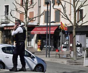Un policía llama por celular después de que un hombre con un cuchillo atacara a residentes que salieron de compras en una población sometida a cuarentena el sábado 4 de abril de 2020 en Romans-sur-Isere, en el sur de Francia.