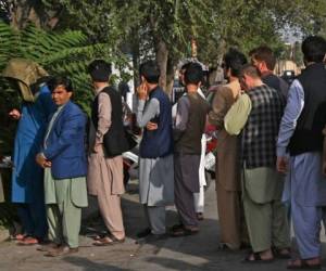 Los afganos hacen cola mientras esperan su turno para cobrar dinero de un cajero automático frente a un banco a lo largo de una carretera en Kabul el 21 de agosto de 2021, días después de la impresionante toma de Afganistán por los talibanes. Foto: AFP