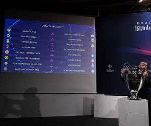 n hombre retira el trofeo de la UEFA Champions League frente a una pantalla que muestra el resultado del sorteo de los octavos de final del torneo de fútbol de la UEFA Champions League 2022-2023 en Nyon el 7 de noviembre de 2022.