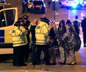 Emergency services personnel speak to people outside Manchester Arena after reports of an explosion at the venue during an Ariana Grande concert in Manchester, England, Monday, May 22, 2017. Several people have died following an explosion Monday night at an Ariana Grande concert in northern England, police and witnesses said. The singer was not injured, according to a representative. (Peter Byrne/PA via AP)