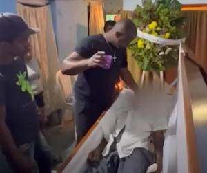 Joven se acerca a Julio Pierra para colocarle un vaso con agua a su boca.