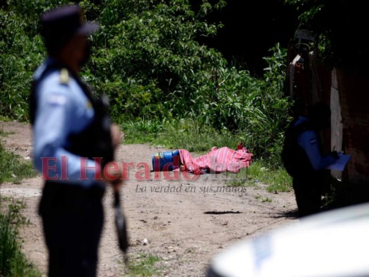 Elementos de la Policía Nacional recogen datos de la escena del crimen. A lo lejos se ve el cadáver de la víctima junto a dos baldes de nacatamales. Foto: Emilio Flores/EL HERALDO.