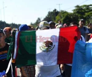 Un migrante hondureño levanta la bandera mexicana y a su lado alguien sostiene la de Guatemala. (Foto: AFP)