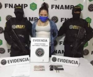 La mujer fue presentada frente a el arma y el dinero decomisados durante su arresto.