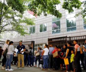 Un funcionario de Inmigración y Control de Aduanas ayuda a las personas que esperan entrar al edificio que alberga a ICE y al tribunal de inmigración. Foto: Agencia AP.
