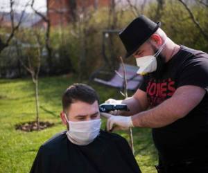 El peluquero de Kosovo, Driton Kameri, usa una máscara facial mientras corta el cabello de un cliente en su jardín el 30 de marzo de 2020 en Pristina durante la pandemia de Covid-19. Foto: Agencia AFP.