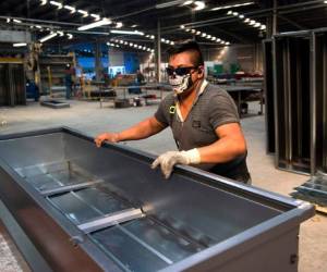 De color café, herrajes brillantes y formas ovaladas, el 'Ataúd Cov' se ensambla con láminas de acero en una bodega de Los Reyes de La Paz, municipio del estado México (centro). AFP.