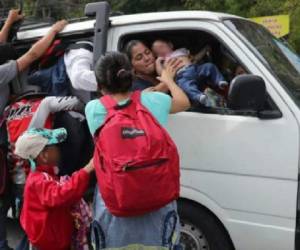 Momento en el que una hondureña le entrega su bebé a su hermana, quien logró abordar un microbús en Zacapa, Guatemala. (Foto Prensa Libre: Érick Ávila)