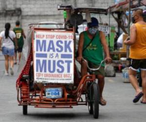 Un hombre maneja un vehículo a pedales con un lema que recuerda a la gente que emplee mascarilla para frenar los contagios de coronavirus, en Manila, Filipinas. Foto: AP