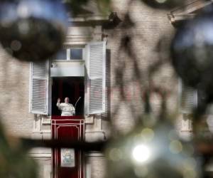 El papa Francisco, enmarcado entre las ramas de un árbol de Navidad, da la bienvenida a los feligreses mientras recita el Angelus desde la ventana de su estudio con vista a la plaza de San Pedro en el Vaticano, el domingo 23 de diciembre de 2018.