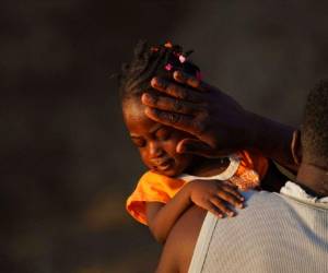 Un hombre lleva a una niña a través del Río Bravo mientras los migrantes, muchos de Haití, abandonan Del Río, Texas, para regresar a Ciudad Acuña, México, la madrugada del miércoles 22 de septiembre de 2021, algunos para evitar una posible deportación de Estados Unidos y otros a conseguir suministros. (AP Foto/Fernando Llano).