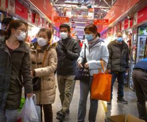 Varias personas con mascarillas compran en un mercado en Beijing donde las medidas de prevención se han extremado para evitar la expansión del virus. Foto: AP.