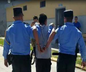 Agentes de la Policía Nacional trasladan hasta la posta del sector al presunto asesino de una mujer de 92 años de edad en Santa Barbara.