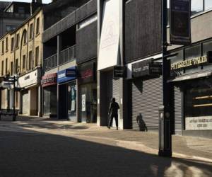 A pedestrian walks past closed shops in Huddersfield, northern England, on April 17, 2020, during the nationwide lockdown to combat the novel coronavirus COVID-19 pandemic. - The number of people in Britain who have died in hospital from coronavirus has risen by 847 to 14,576, according to daily health ministry figures released on Friday. (Photo by Oli SCARFF / AFP)