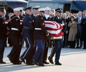 Los miembros de la familia ven cómo el ataúd cubierto con la bandera del expresidente de los Estados Unidos, George H.W. Bush, es transportado por una guardia de honor militar de servicios conjuntos durante una ceremonia de llegada el lunes 3 de diciembre de 2018 en la Base de la Fuerza Aérea Andrews en Maryland. (Foto: AFP)