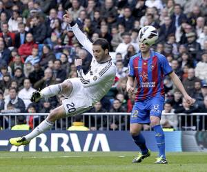 Real Madrid's Gonzalo Higuain, left, from Argentina, scores a goal under pressure from Levante's Christian Lell, from Germany during a Spanish La Liga soccer match at the Santiago Bernabeu stadium in Madrid, Spain, Saturday, April 6, 2013. (AP Photo/Andres Kudacki)